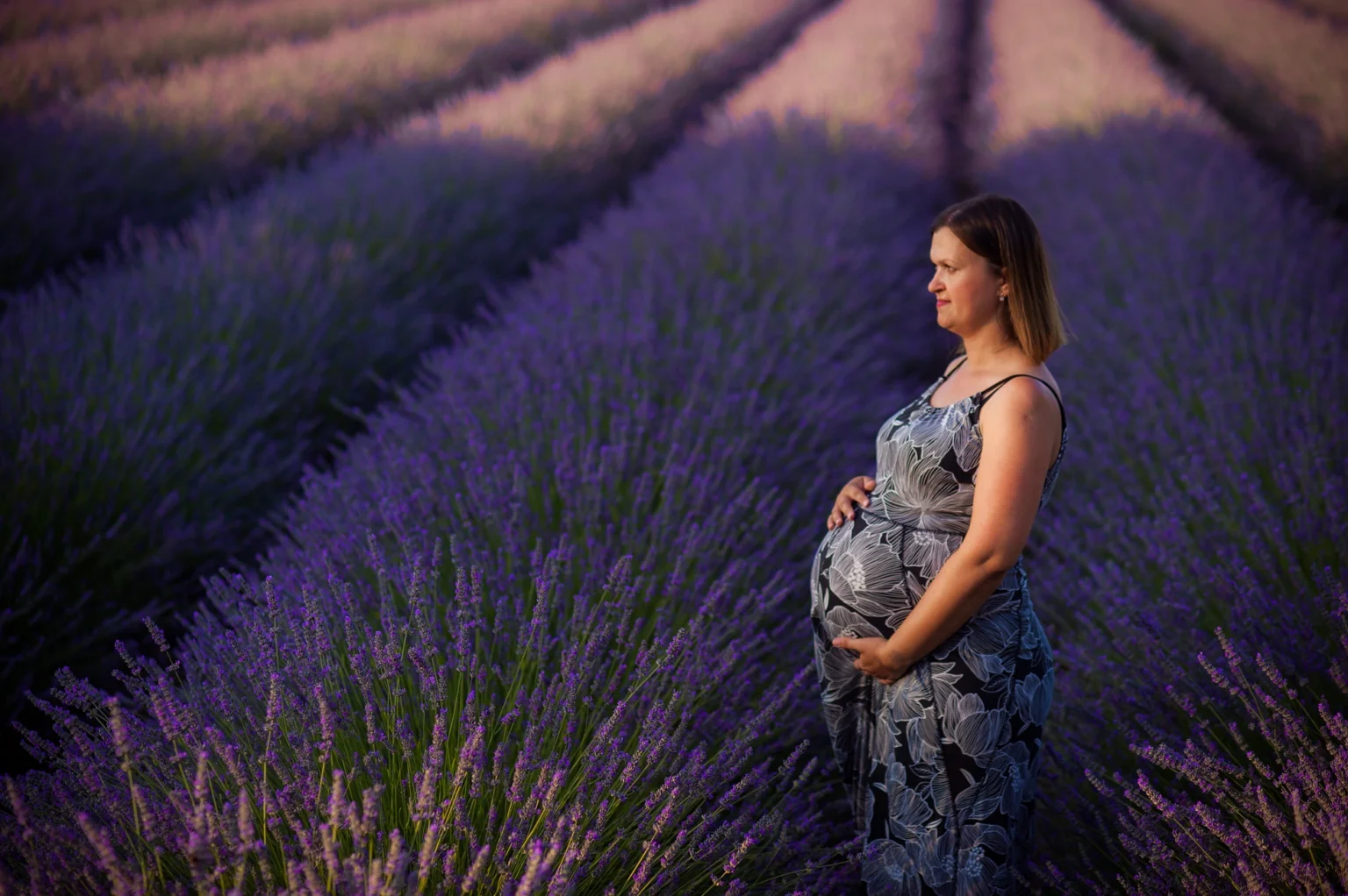 Pregnant woman posing in a field in Vienna during a photo shoot. The image captures her graceful and serene appearance in a natural, outdoor setting