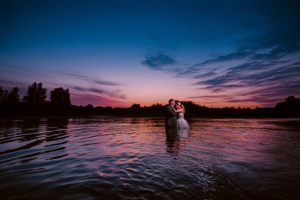 Romantic sunset wedding by the Danube River in Vienna, Austria. The bride and groom are captured against a breathtaking sunset backdrop, with the serene river adding a touch of elegance to their special day.
