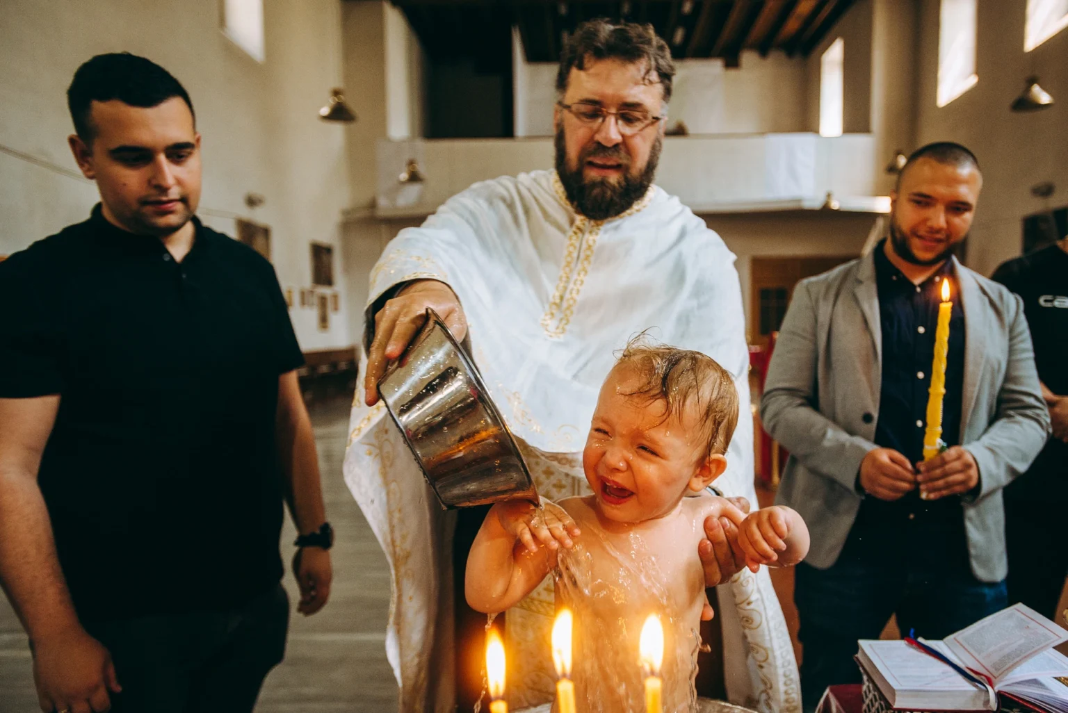 Child being baptized in a Roman Catholic church in Vienna. The image captures the sacred moment of the baptism ceremony in a historic church setting.