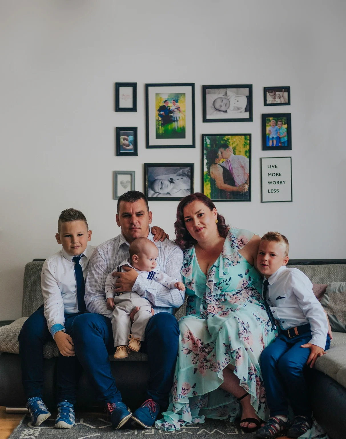 Family with three kids posing at home in Vienna during the baptism of the youngest child. The image captures their joyful and together moment in a comfortable home setting.