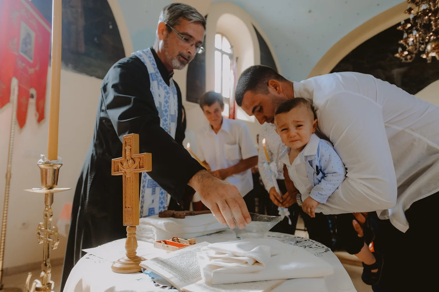 Young child being baptized at St. Stephen's Cathedral in Vienna. The image captures the sacred moment of the baptism ceremony in the historic church