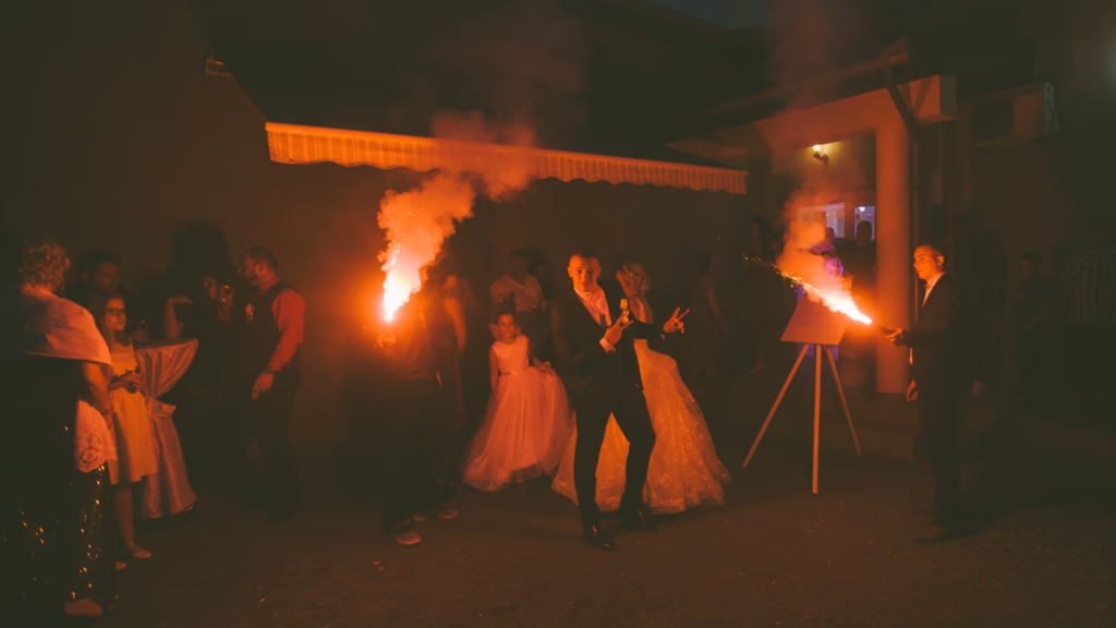 A bridal party gathered around the newlyweds, laughing, cheering, and raising their glasses in a luxurious wedding reception setting, capturing the energy of celebration.