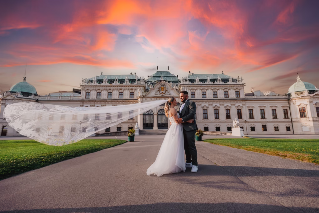 Newlyweds posing in front of the majestic Schönbrunn Palace in Vienna, creating a fairytale wedding scene
