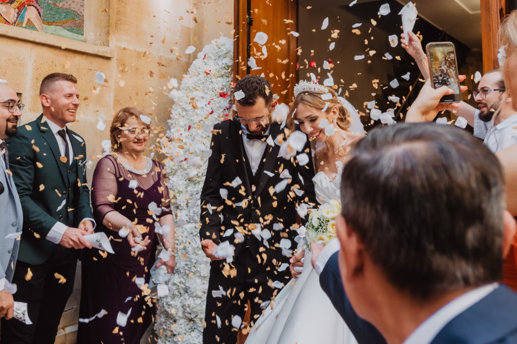 A bride and groom laughing and embracing as golden confetti rains down around them, capturing the pure joy and elegance of their luxury wedding celebration.