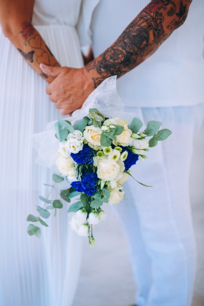 A close-up of a bride’s hands holding a luxury floral bouquet, with delicate flowers framing her engagement ring and wedding dress details.