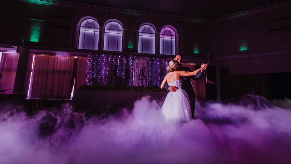 Bride and groom’s first dance under golden lights at their wedding reception, surrounded by candlelit tables and a romantic ambiance. Captured by wedding photographer Vinko Jovanovac, showcasing the beauty of timeless wedding moments.
