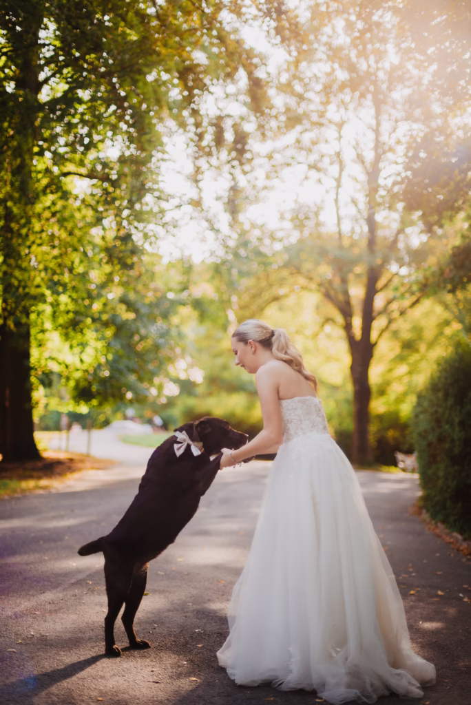A bride in a flowing wedding gown dancing with her dog, her gown twirling as her pet excitedly joins in, capturing a luxury wedding moment filled with warmth and joy.
